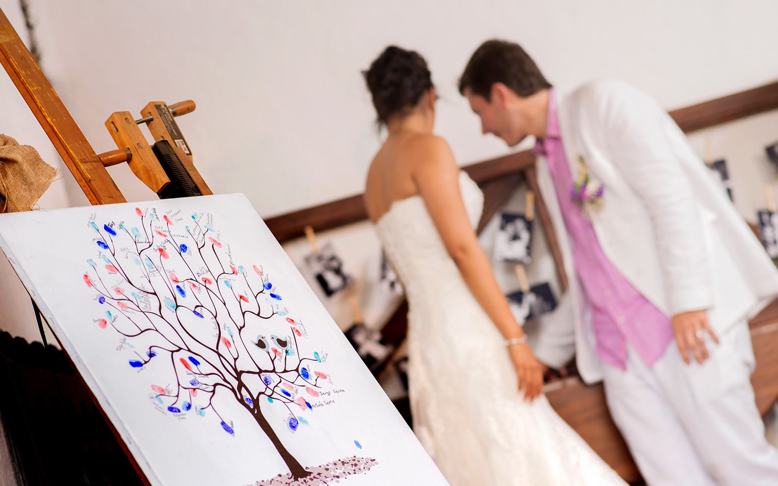 Árbol de huellas firmado por los invitados en primer plano, con los novios desenfocados al fondo